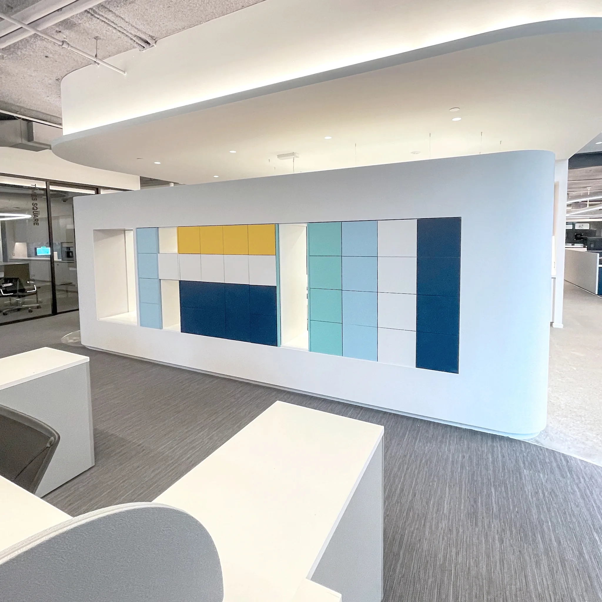 Colorful lockers embedded inside curved white pod wall in open office